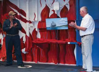 Commander Sameer Khanna of the USS Pearl Harbor (left) and combat artist Douglas Rowe unveil a reproduction of Rowe’s new painting for the Navy’s art collection. 