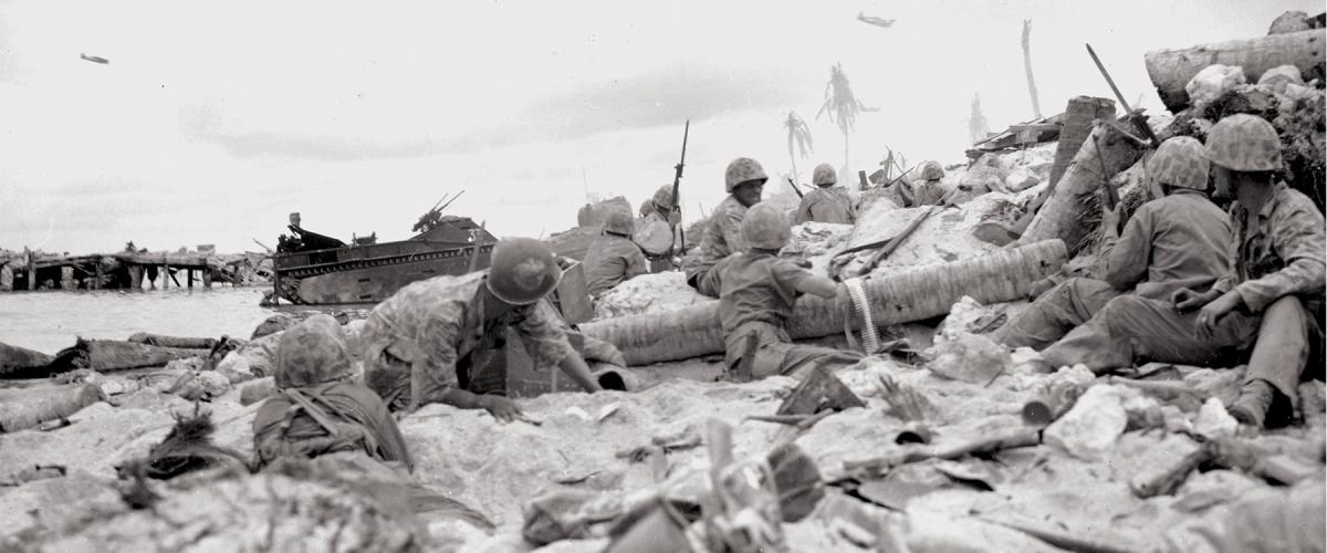 Marines on the beach at Tarawa Atoll's Betio Island duck for cover as their dive-bombers roar in overhead to blast Japanese positions, November 1943.