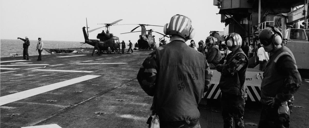 Helicopters are lined up on the deck of the USS Guam (LPH-9) for servicing between missions off the coast of Grenada, 25 October 1983.